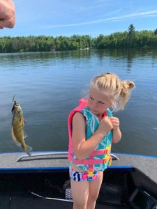 young girl in a boat trying to keep away from a fish